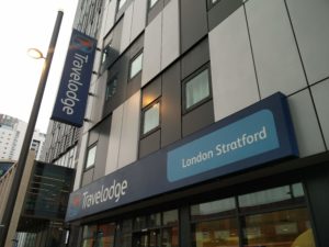 A closer view of the entrance signs for the Travelodge Stratford hotel